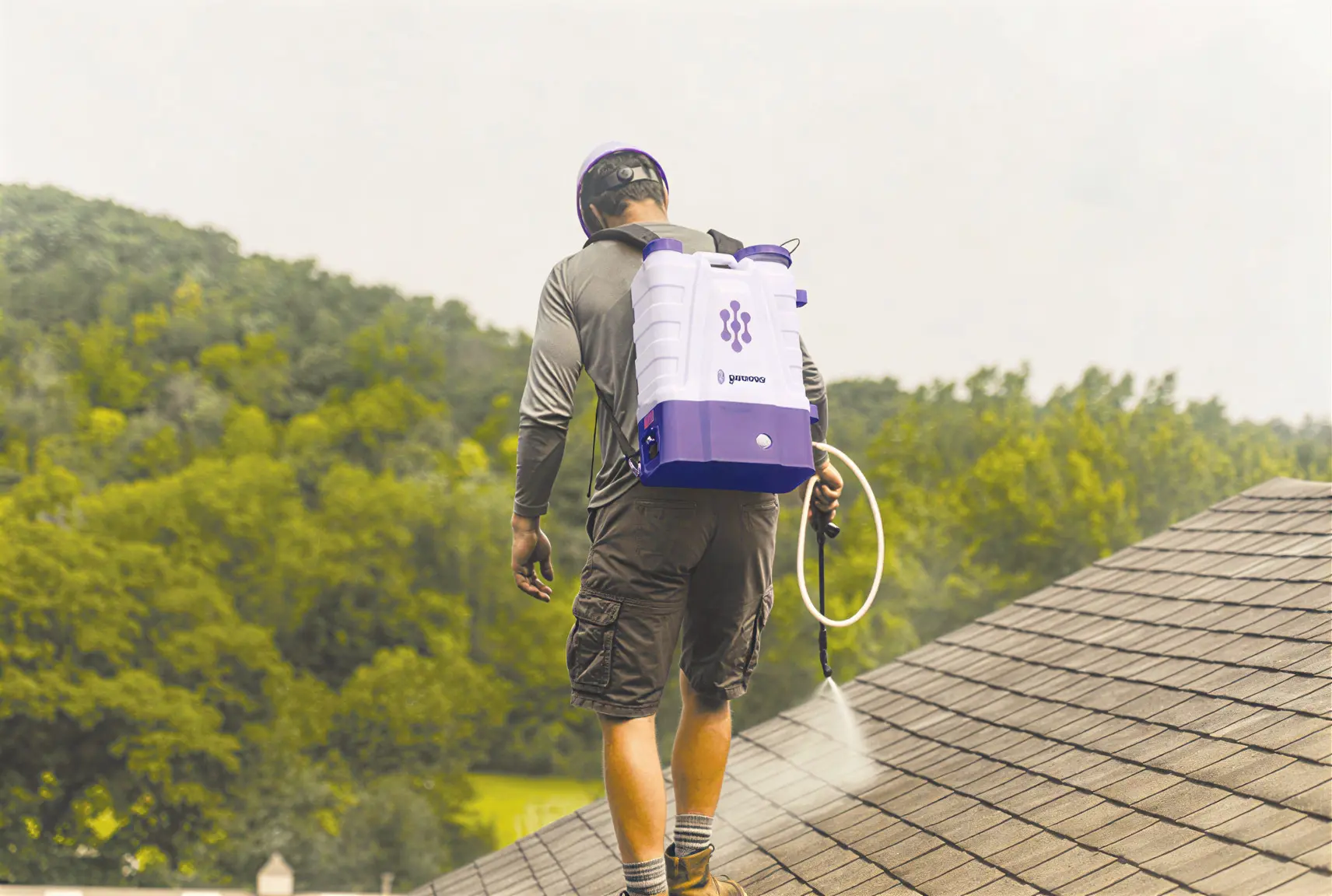 Worker spraying roof with backpack sprayer
